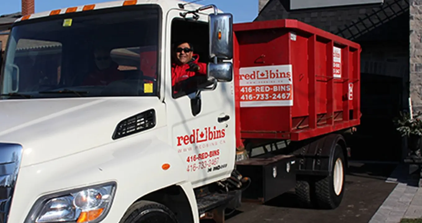 Environmental disposal, a truck driver delivering a disposal red garbage bin